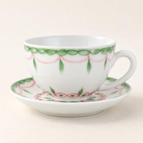 AI-assisted concept image of a white cup and saucer with pink swags and green leaf details.