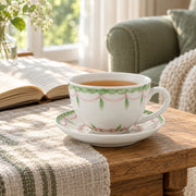 AI-assisted concept image of the pink and green cup and saucer beside an open book.