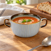 AI-assisted illustration of Mist Blue Double-Handled Soup Cup, tomato lunch setting; food and styling props are not included.