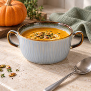 AI-assisted illustration of Mist Blue Double-Handled Soup Cup, pumpkin kitchen setting; food and styling props are not included.