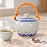 AI-assisted concept image of rice-grain teapot — orange handle: styled setting view; food and props are not included.